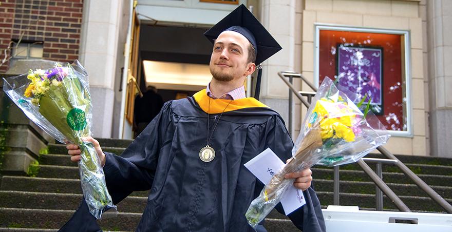 A student walking out of McKinley Hall after receiving his hood at SPU's graduate hooding ceremony